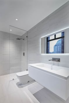 a white bathroom with a large mirror above the sink and a walk - in shower