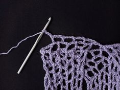 the crochet pattern is being worked on with a knitting needle and yarn ball