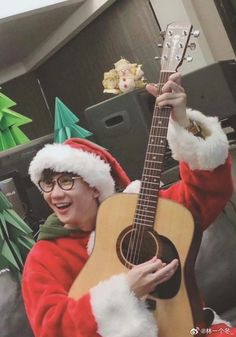 a man dressed as santa claus holding an acoustic guitar