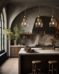 a kitchen with three hanging lights over the island and two stools in front of it