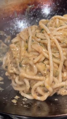 noodles are being cooked in a wok on the stove