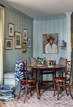 a dining room table with chairs and pictures on the wall above it, along with other furniture