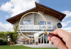 a person holding a magnifying glass in front of a house