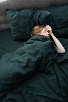 a woman laying in bed under a blanket