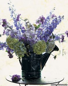 a watering can filled with purple and white flowers