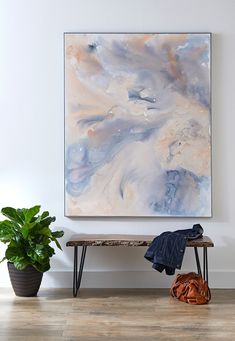 a painting hanging on the wall next to a bench and potted plant in front of it