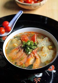 a bowl of soup with shrimp, potatoes and tomatoes