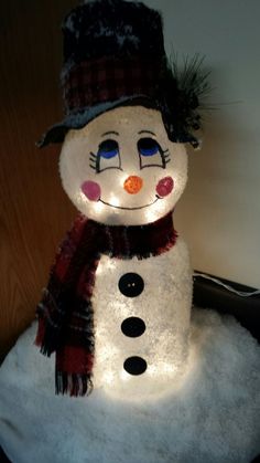 a lighted snowman sitting on top of a pile of snow