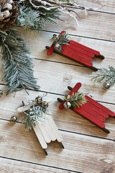 three red and white popsicle christmas ornaments on a wooden table next to pine cones