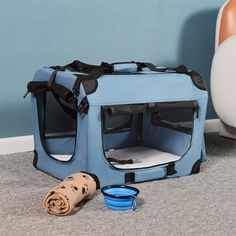 a blue pet carrier sitting on the floor next to a dog bowl and water bottle