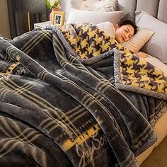 a woman laying in bed under a blanket with pillows and blankets on top of it