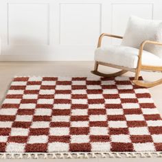 a rocking chair sitting on top of a wooden floor next to a white and red rug