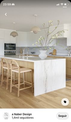 an image of a kitchen with white cabinets and marble counter tops, as well as wooden stools