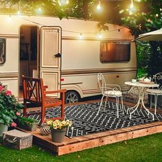 an rv is parked in the backyard with chairs and tables