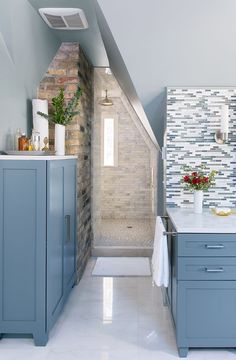 a kitchen with blue cabinets and white counter tops in an attic type space that also has a skylight above the sink