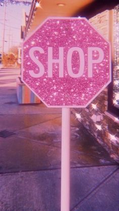 a pink and white stop sign sitting on the side of a road next to a building