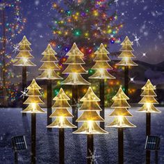 lighted christmas trees on poles in front of a snow covered tree with stars and lights