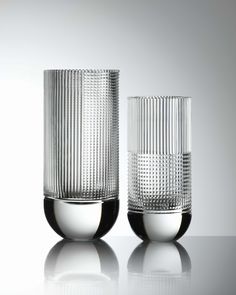 two clear glass vases sitting on top of a white table next to each other