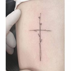 a small cross tattoo on the side of a woman's lower back ribcage