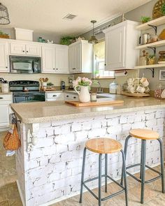 A wraparound kitchen counter with a brown solid surface countertop has been converted to a stylish dining area with a whitewashed faux brick back panel and a wooden corbel accent. A side-mounted towel rack provides handy storage, while two wooden stools create a convenient place to sit...   Image: athomeinthewildwood