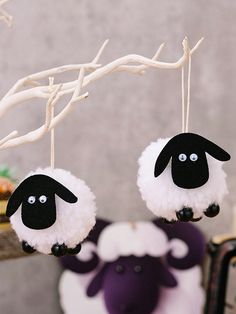 two black and white sheep ornaments hanging from a tree branch with branches in the background