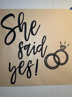 a sign that says she said yes with two wedding rings on it