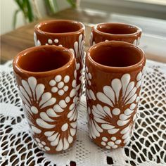 four brown and white vases sitting on top of a doily covered tablecloth