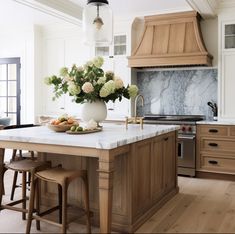 a kitchen island with marble counter tops and wooden stools in front of an oven