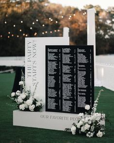 an outdoor ceremony with white flowers and greenery on the grass is decorated with black and white seating signs