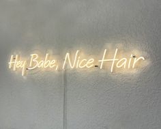 a neon sign that says hey babe, nice hair on the wall in front of it