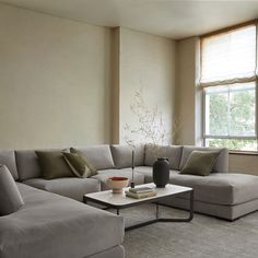 a living room with a sectional couch and coffee table in front of a large window