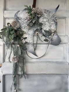 a white mask with flowers and greenery hanging on a door