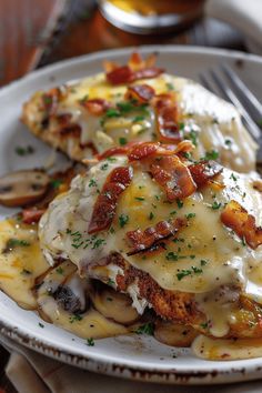 a white plate topped with ravioli covered in cheese and bacon next to a fork