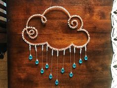 a wooden table topped with a cloud shaped brooch and chain hanging from it's side