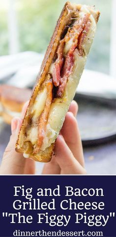 a person holding up a bacon and cheese sandwich in front of a plate with other food on it