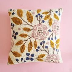 an embroidered pillow on a pink background