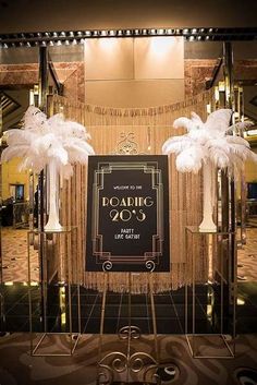 an entrance to a building decorated with tall white feathers and chandeliers, in front of a sign that reads roaring 20s