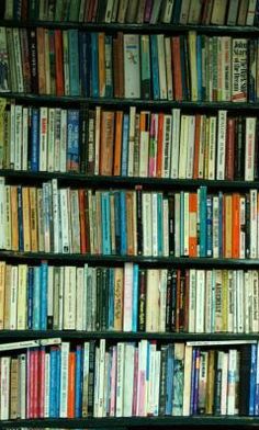 a book shelf filled with lots of different colored books on top of eachother