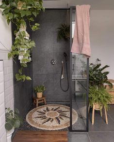 a walk in shower sitting next to a bathroom with plants on the side of it