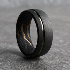 a black and gold wedding band with wood inlays on the inside of it