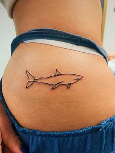 a woman's stomach with a small tattoo of a shark on the lower back