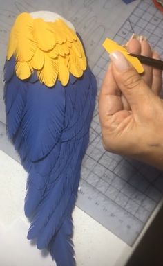 a person holding a pencil near a blue and yellow bird