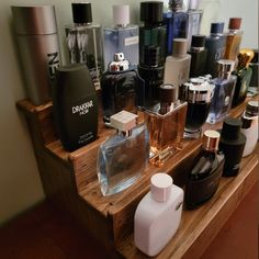 many different types of perfume bottles on a wooden shelf