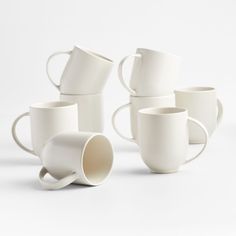 six white coffee mugs stacked on top of each other in different shapes and sizes