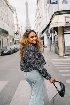 a woman is standing on the street with her hand in her pocket