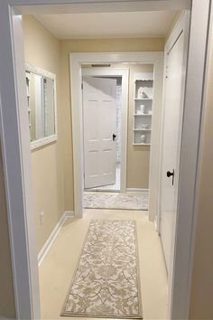 an empty hallway with white doors and beige carpet