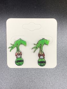 "The Grinch Hand Holding Green Diamond Ornament With Red Bow That Says \"Grinch\"  Sealed With Resin  Posts With Rubber Push Back" The Grinch Hand, Grinch Hand, Grinch Hands, The Grinch, Hand Holding, Green Diamond, Red Bow, Jewelry Earrings Studs, Grinch