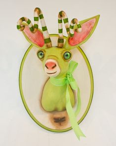 a ceramic deer head with green and white stripes on it's antlers, holding a bow