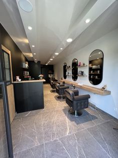 a hair salon with chairs and mirrors on the wall next to each other in front of a counter