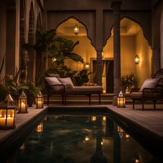 an indoor swimming pool with candles lit in the middle and two chaise lounges next to it